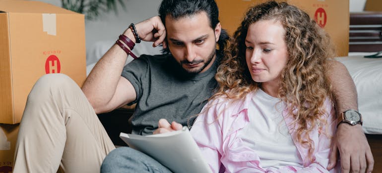A couple making a list of pros and cons between hiring affordable movers vs DIY moving