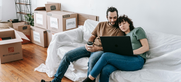 Couple sitting on a couch browsing on computer for a budget-friendly sustainable packing options for a move